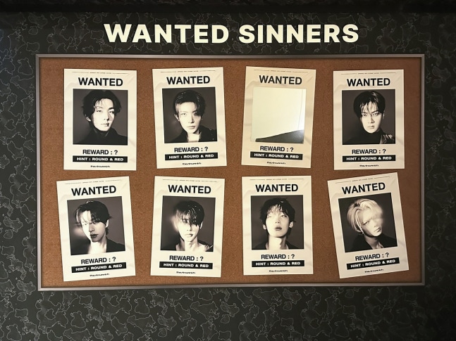 A bulletin board titled "WANTED SINNERS" displays eight stylized black-and-white wanted posters, each featuring a portrait except one blank poster. All posters include the phrase "WANTED," a reward marked with a question mark, and the hint "ROUND & RED."