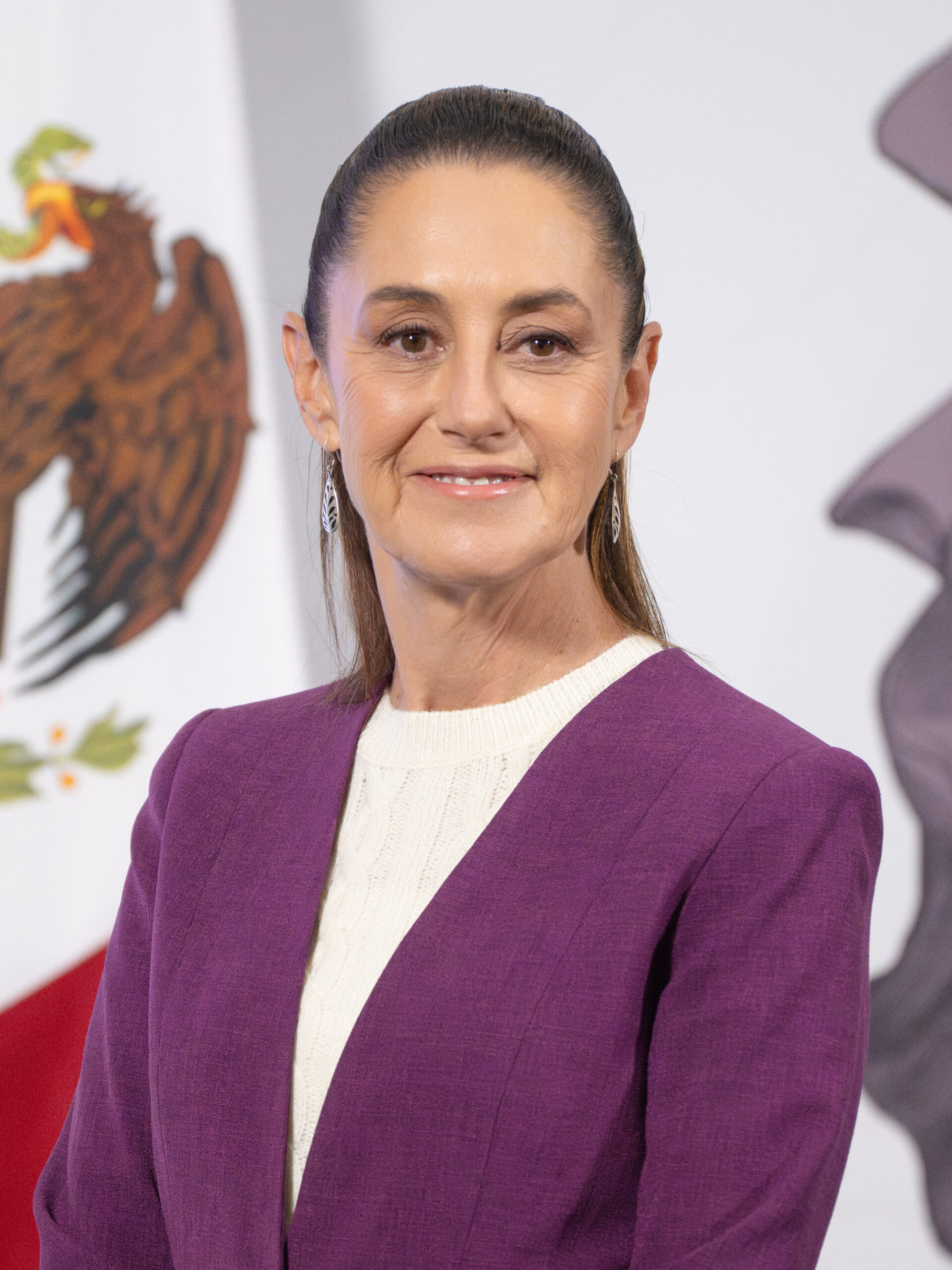 Mexican President Claudia Sheinbaum poses before her country national glag.