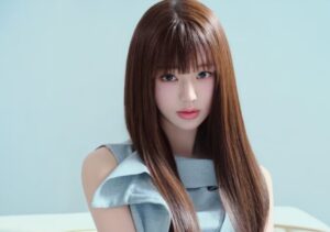 Jang Wonyoung with long straight brown hair and bangs, wearing a light blue sleeveless outfit, posing against a soft blue background. The photo was taken after donating a 200 million KRW to Yonsei Severance Hospital.