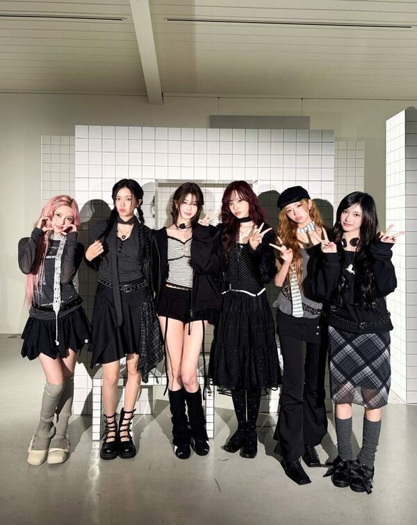 IVE members in coordinated black and gray fashion outfits standing against a minimalist tiled wall backdrop.
