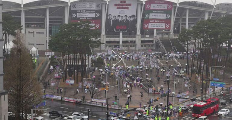 Fans with umbrellas gather outside Goyang Stadium in rainy weather ahead of BTS’s “Arirang” world tour concert.