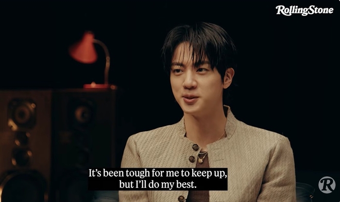 BTS Jin speaks in a Rolling Stone interview, wearing a light jacket, with caption text about his struggles.