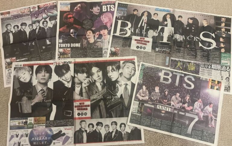 Japanese newspapers laid out featuring BTS with large group and solo photos, headlines highlighting their Tokyo Dome concerts and global success.