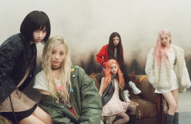 Five ILLIT members pose together in a smoky, conceptual room with edgy fashion and colorful hairstyles.