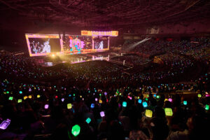 KSPO Dome filled with fans waving colorful light sticks as NCT WISH performs on stage.