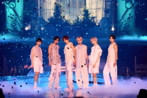 NCT WISH performs in coordinated pastel outfits on stage with confetti falling around them.