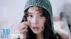 Member in green crocheted hat playfully places dog and eye stickers on face indoors.