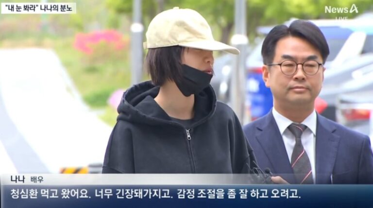 Nana appears outdoors during a news interview, standing beside her lawyer in a suit.