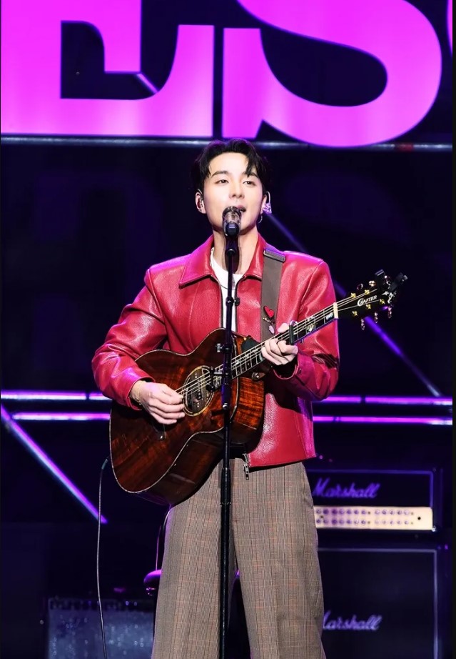 Roy Kim performs live at Lovesome Festival 2026, playing guitar in a vibrant stage setting.