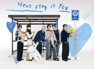 TWS members pose at a bus stop set with heart illustrations, holding a bear and flowers.