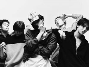 CORTIS members pose dynamically in a black‑and‑white editorial photo with varied gestures and expressions.