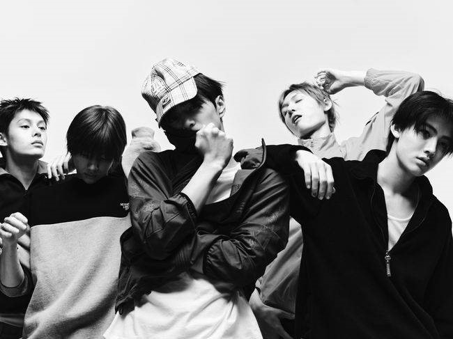 CORTIS members pose dynamically in a black‑and‑white editorial photo with varied gestures and expressions.