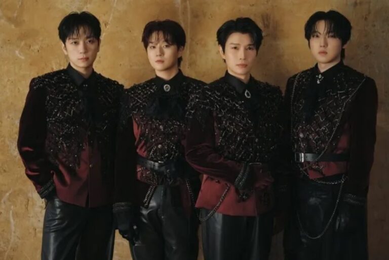 Forestella members pose in ornate burgundy velvet jackets and black leather pants against a textured wall.