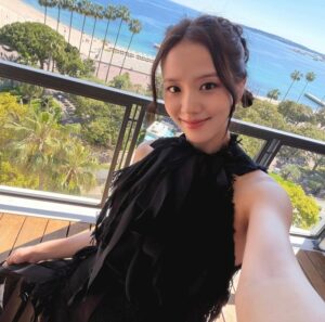 Jisoo takes a selfie on a balcony overlooking palm trees and the Cannes coastline.