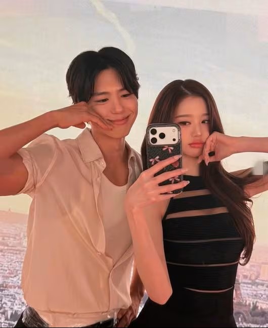IVE’s Jang Wonyoung and Park Bo‑gum pose playfully together in a selfie, highlighting their visuals and chemistry.