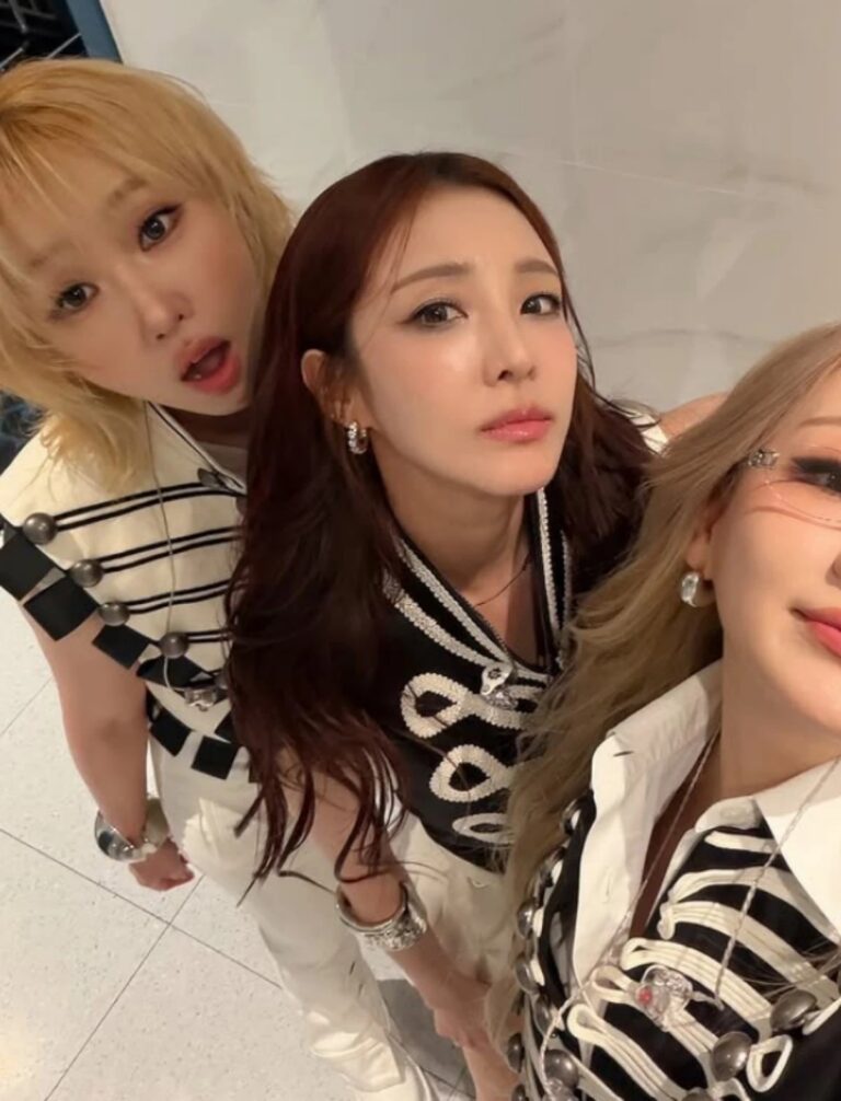 CL, Sandara Park, and Minzy pose together in coordinated black-and-white outfits, taking a close selfie indoors.