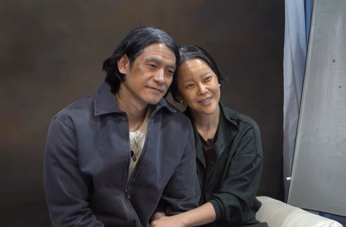 Baek Ji‑young and Jung Suk‑won sit closely side by side, styled with gray streaks to resemble aging.