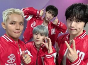 CIX members pose together in matching red varsity jackets against a purple backdrop, making playful hand signs.