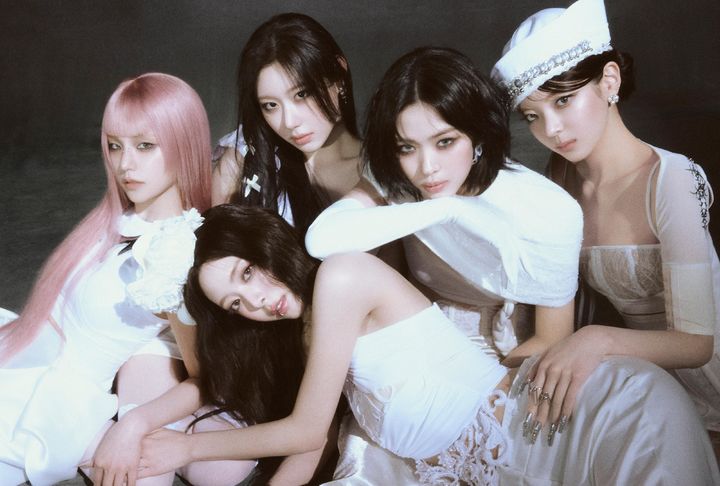ITZY members pose closely together in elegant white outfits, exuding a confident and emotional aura.