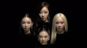 Four aespa members’ faces dramatically lit against a black background, arranged symmetrically in a diamond formation, exuding a mysterious and powerful aura.