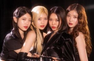 CrazAngel members in dark, stylish outfits against a dramatic background, highlighted by warm lighting.