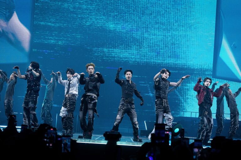ENHYPEN performing on stage in Seoul with synchronized choreography, futuristic outfits, and a digital screen backdrop during their BLOOD SAGA world tour. Caption: ENHYPEN electrifies fans in Seoul with powerful performances as they kick off the BLOOD SAGA world tour, highlighting their unity as a six-member lineup.