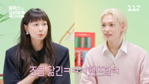 Felix and Lee Na‑young sit together against a pastel backdrop, sharing lighthearted conversation.