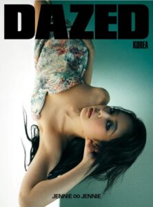 Jennie lies gracefully in a textured multicolored garment under soft lighting for Dazed Korea, her gaze upward and serene.