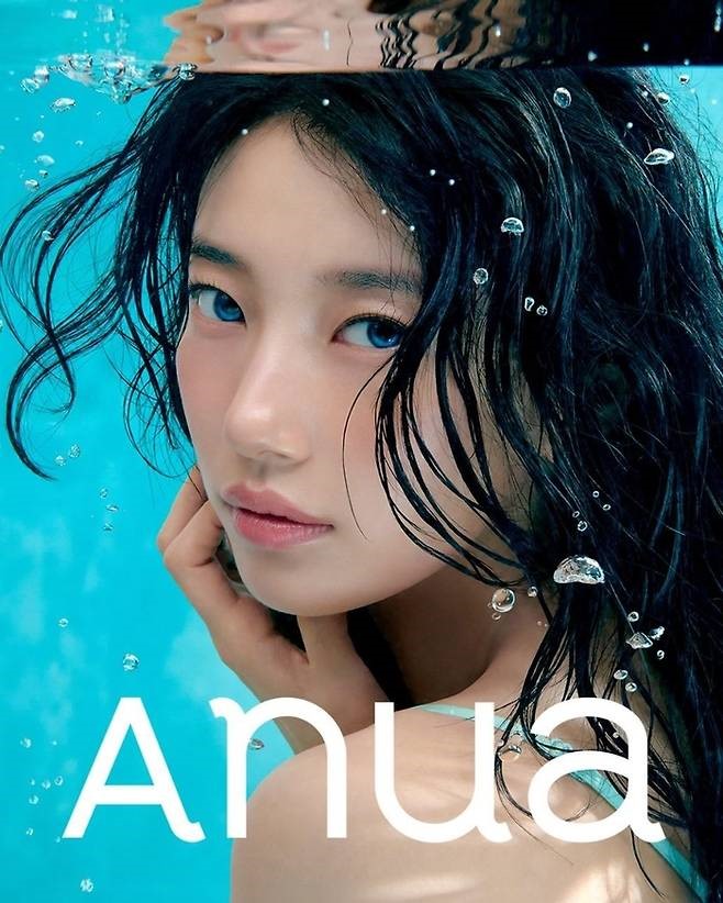 Suzy poses underwater with wet hair and a serene expression, surrounded by bubbles against a turquoise backdrop, with the word “Anua” displayed below.