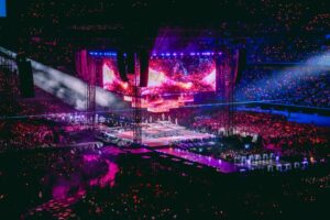A packed stadium glows with pink and purple lights during TWICE’s large‑scale concert.