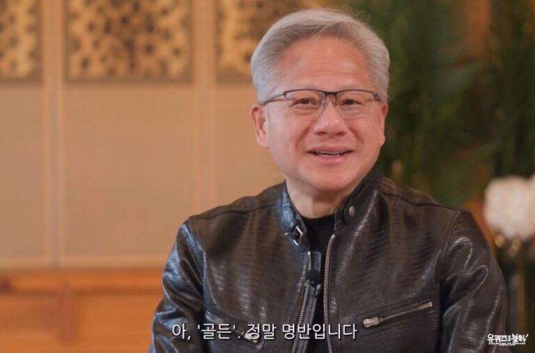 NVIDIA CEO Jensen Huang sits indoors wearing a black leather jacket and glasses, smiling during a Korean TV interview. Korean subtitles read “Ah, ‘Golden.’ It’s truly a masterpiece album.