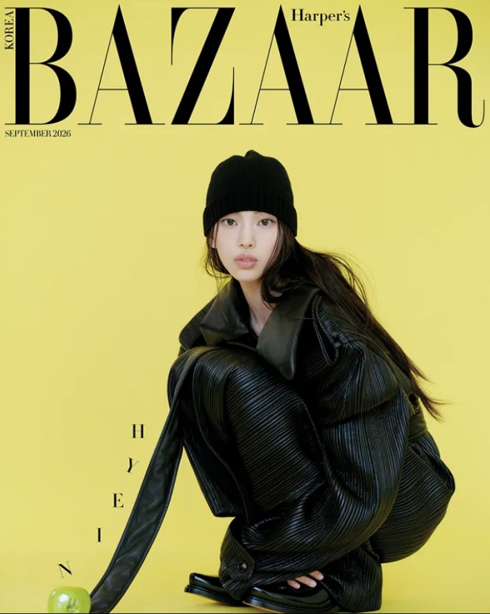 NewJeans’ Hyein in a black leather outfit and knit beanie crouching on a bright yellow background, Harper’s Bazaar Korea September 2026 cover.