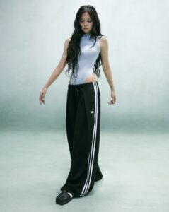 ennie from Blackpink poses in a sleek gray bodysuit with black Adidas track pants, blending sporty and high-fashion style.