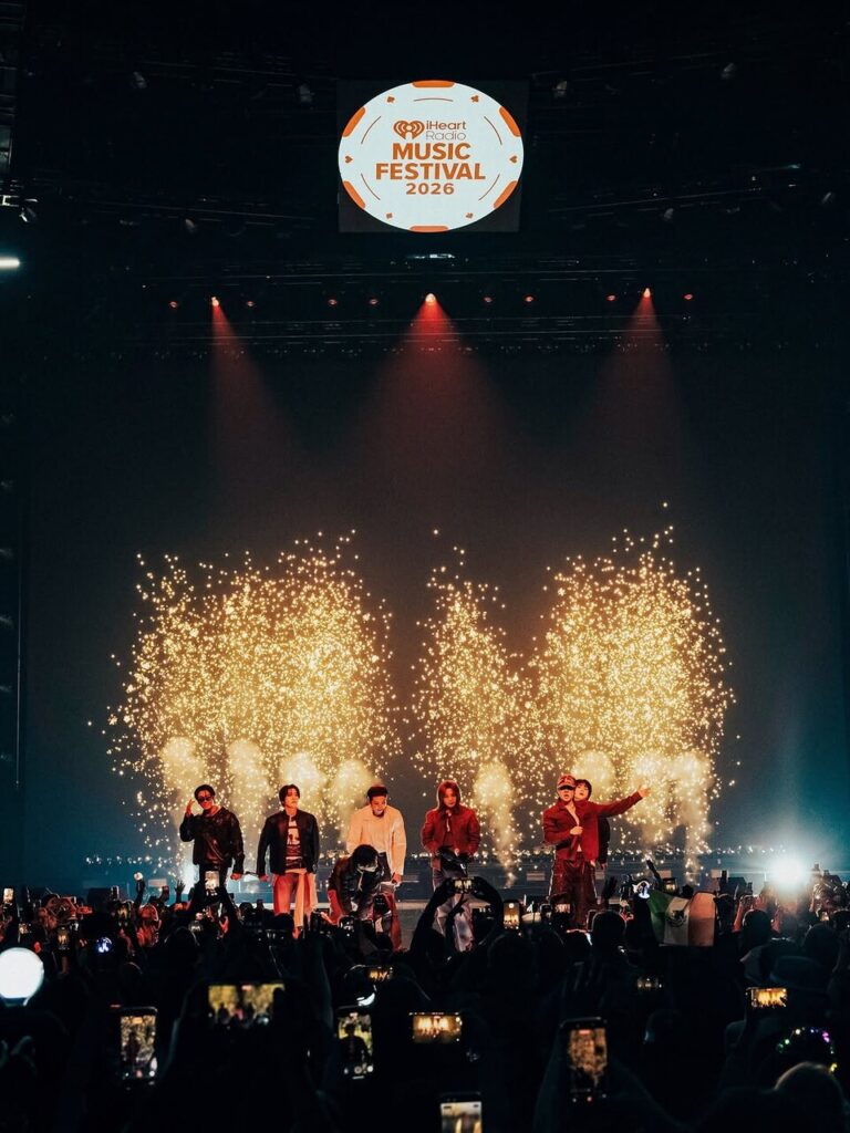 BTS performs beneath the 2026 iHeartRadio Music Festival logo as fireworks light up the stage