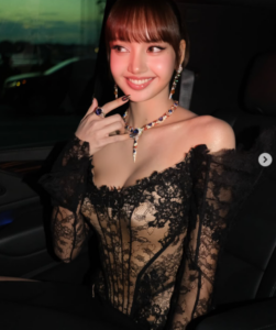 BLACKPINK’s Lisa smiles in a black lace outfit while sitting inside a car.